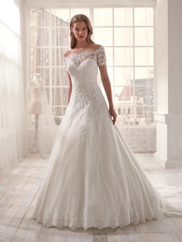 Romantic mermaid wedding dress of light pink Chantilly lace with plunging V-neck that continues on the sleeves. The keyhole opening in back and the tulle overskirt add romanticism to this dreamy dress.
