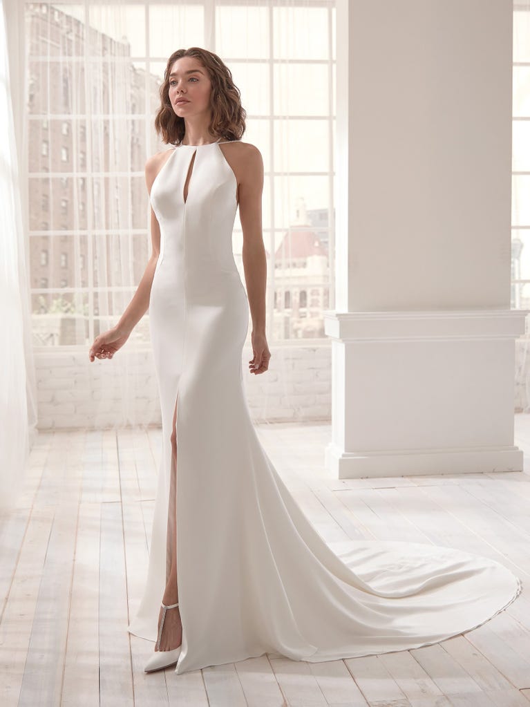 Romantic mermaid wedding dress of light pink Chantilly lace with plunging V-neck that continues on the sleeves. The keyhole opening in back and the tulle overskirt add romanticism to this dreamy dress.