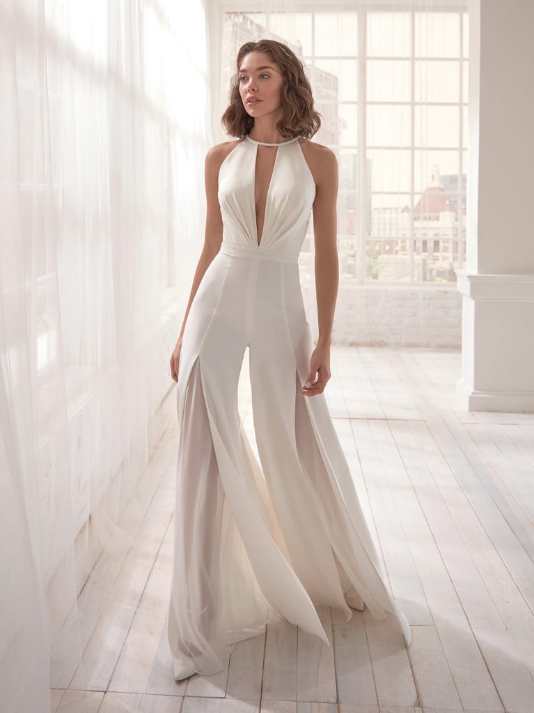 Romantic mermaid wedding dress of light pink Chantilly lace with plunging V-neck that continues on the sleeves. The keyhole opening in back and the tulle overskirt add romanticism to this dreamy dress.
