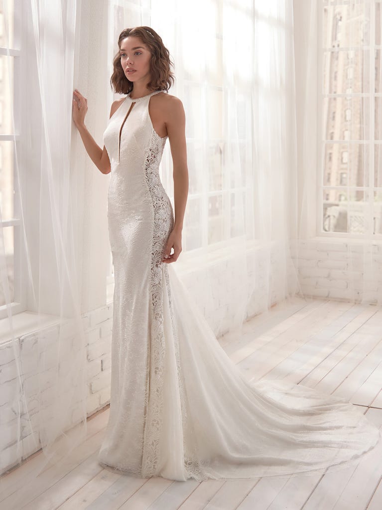 Romantic mermaid wedding dress of light pink Chantilly lace with plunging V-neck that continues on the sleeves. The keyhole opening in back and the tulle overskirt add romanticism to this dreamy dress.