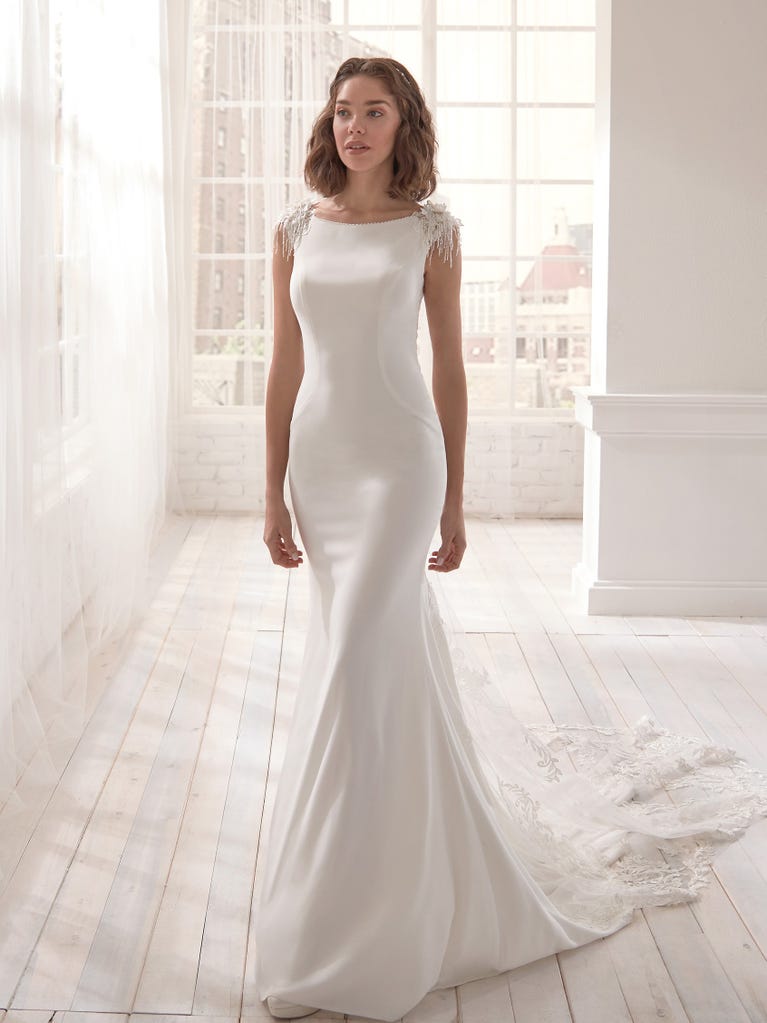 Romantic mermaid wedding dress of light pink Chantilly lace with plunging V-neck that continues on the sleeves. The keyhole opening in back and the tulle overskirt add romanticism to this dreamy dress.
