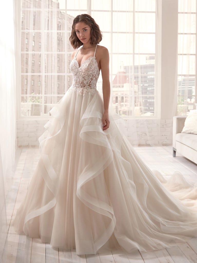 Romantic mermaid wedding dress of light pink Chantilly lace with plunging V-neck that continues on the sleeves. The keyhole opening in back and the tulle overskirt add romanticism to this dreamy dress.