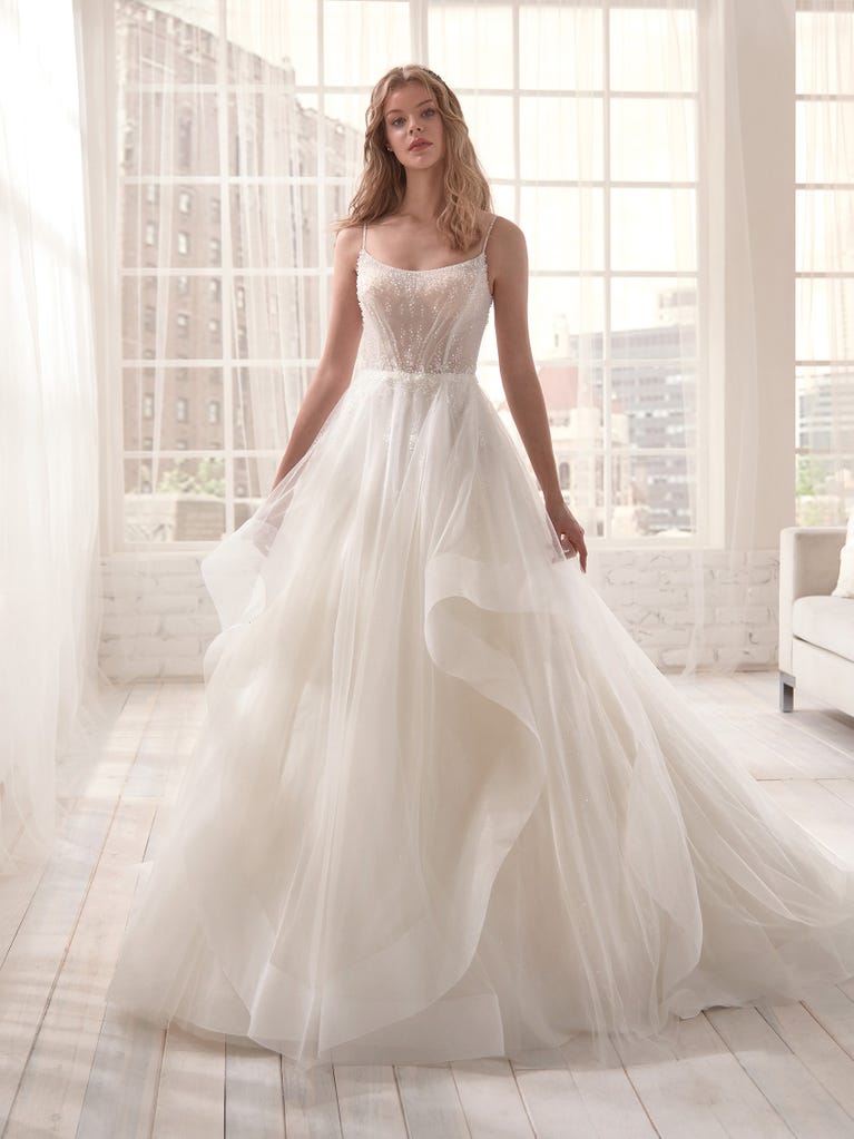 Romantic mermaid wedding dress of light pink Chantilly lace with plunging V-neck that continues on the sleeves. The keyhole opening in back and the tulle overskirt add romanticism to this dreamy dress.
