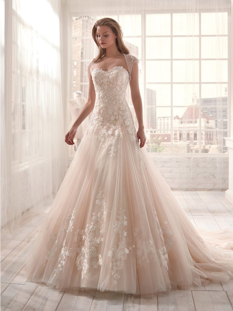 Romantic mermaid wedding dress of light pink Chantilly lace with plunging V-neck that continues on the sleeves. The keyhole opening in back and the tulle overskirt add romanticism to this dreamy dress.