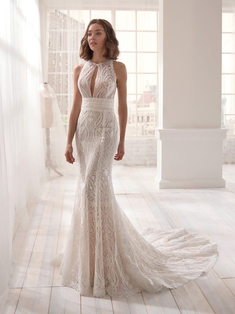 Romantic mermaid wedding dress of light pink Chantilly lace with plunging V-neck that continues on the sleeves. The keyhole opening in back and the tulle overskirt add romanticism to this dreamy dress.