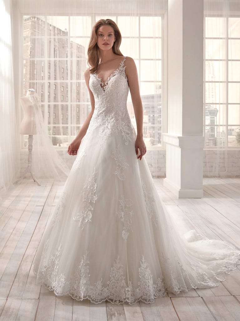 Romantic mermaid wedding dress of light pink Chantilly lace with plunging V-neck that continues on the sleeves. The keyhole opening in back and the tulle overskirt add romanticism to this dreamy dress.