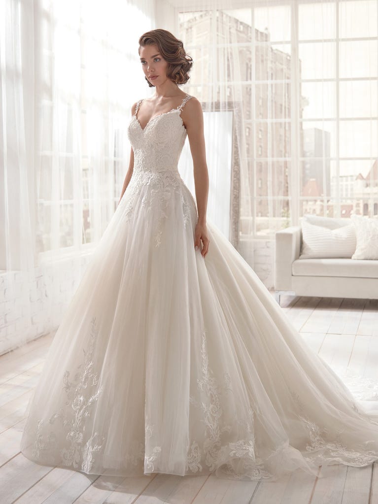 Romantic mermaid wedding dress of light pink Chantilly lace with plunging V-neck that continues on the sleeves. The keyhole opening in back and the tulle overskirt add romanticism to this dreamy dress.