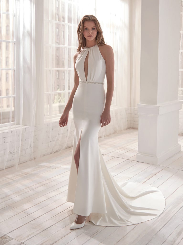 Romantic mermaid wedding dress of light pink Chantilly lace with plunging V-neck that continues on the sleeves. The keyhole opening in back and the tulle overskirt add romanticism to this dreamy dress.