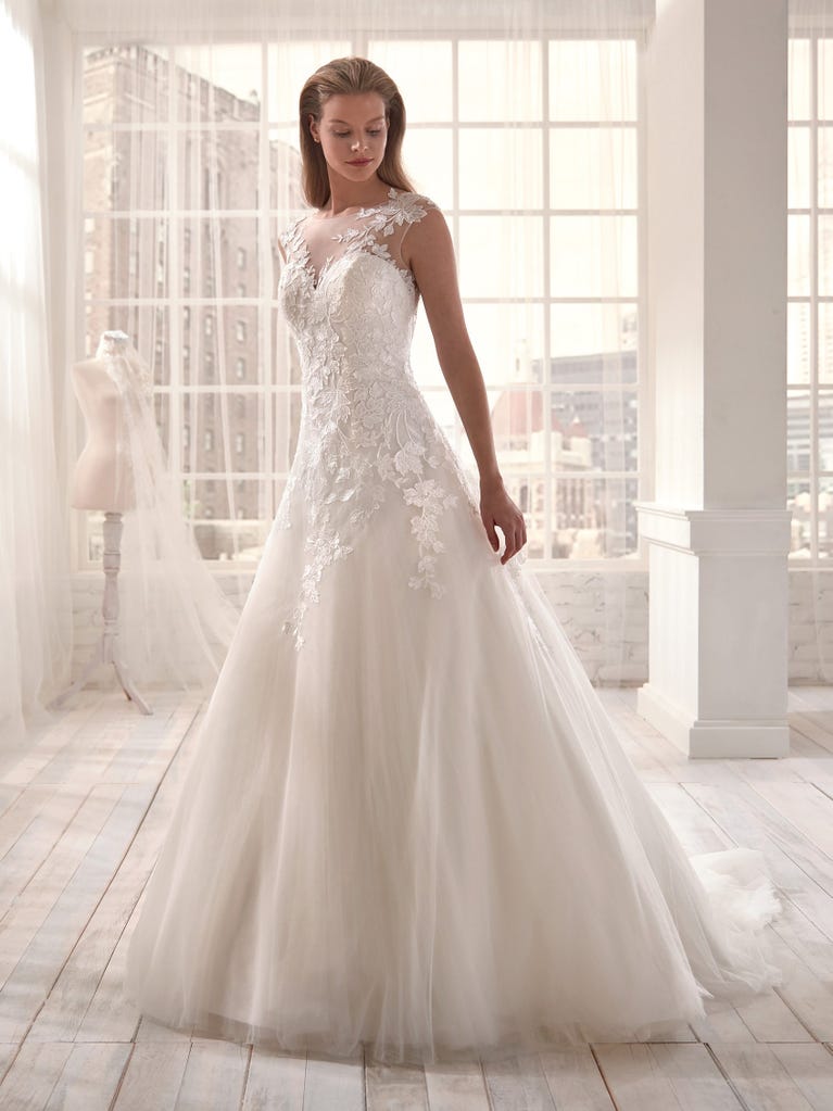 Romantic mermaid wedding dress of light pink Chantilly lace with plunging V-neck that continues on the sleeves. The keyhole opening in back and the tulle overskirt add romanticism to this dreamy dress.
