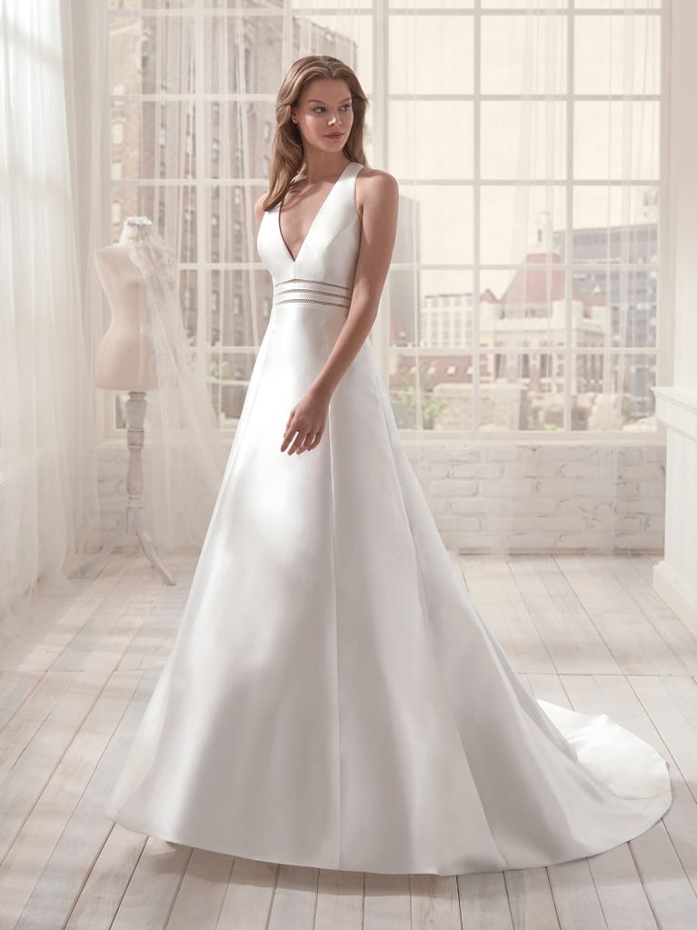 Romantic mermaid wedding dress of light pink Chantilly lace with plunging V-neck that continues on the sleeves. The keyhole opening in back and the tulle overskirt add romanticism to this dreamy dress.