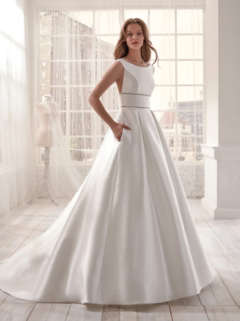 Romantic mermaid wedding dress of light pink Chantilly lace with plunging V-neck that continues on the sleeves. The keyhole opening in back and the tulle overskirt add romanticism to this dreamy dress.