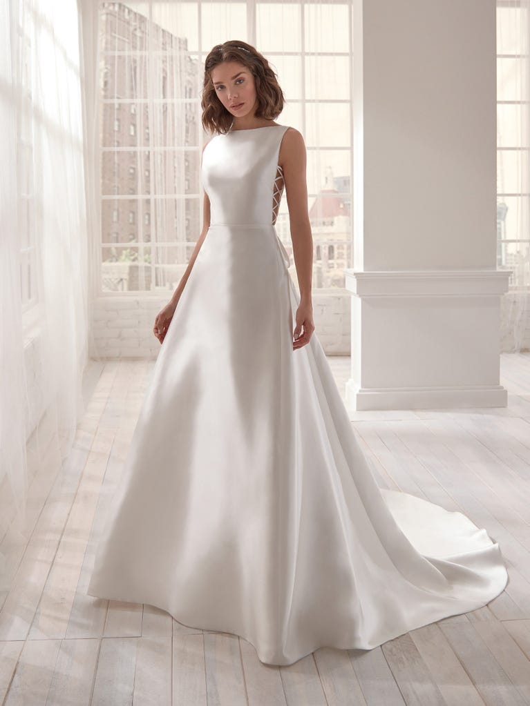 Romantic mermaid wedding dress of light pink Chantilly lace with plunging V-neck that continues on the sleeves. The keyhole opening in back and the tulle overskirt add romanticism to this dreamy dress.