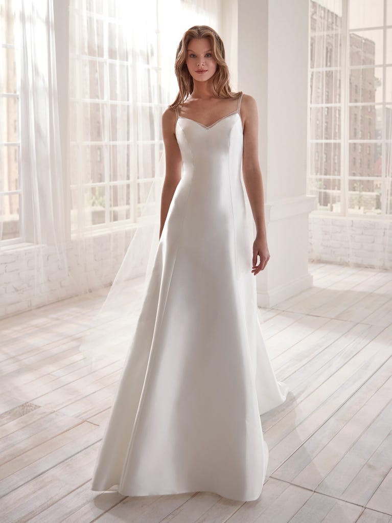 Romantic mermaid wedding dress of light pink Chantilly lace with plunging V-neck that continues on the sleeves. The keyhole opening in back and the tulle overskirt add romanticism to this dreamy dress.