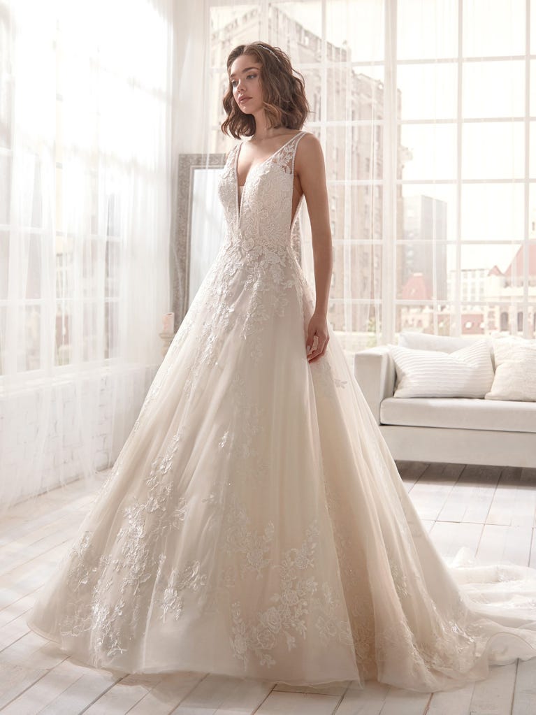Romantic mermaid wedding dress of light pink Chantilly lace with plunging V-neck that continues on the sleeves. The keyhole opening in back and the tulle overskirt add romanticism to this dreamy dress.