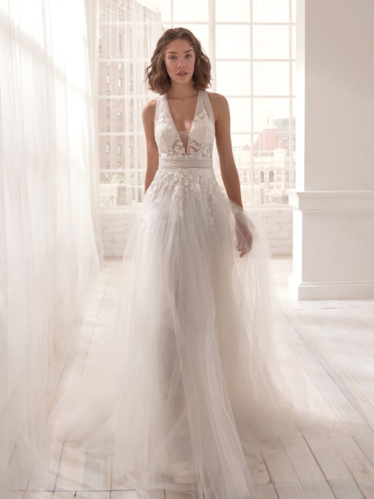 Romantic mermaid wedding dress of light pink Chantilly lace with plunging V-neck that continues on the sleeves. The keyhole opening in back and the tulle overskirt add romanticism to this dreamy dress.