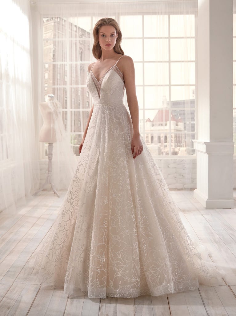 Romantic mermaid wedding dress of light pink Chantilly lace with plunging V-neck that continues on the sleeves. The keyhole opening in back and the tulle overskirt add romanticism to this dreamy dress.