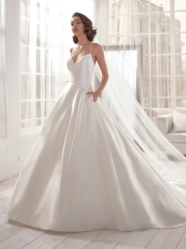 Romantic mermaid wedding dress of light pink Chantilly lace with plunging V-neck that continues on the sleeves. The keyhole opening in back and the tulle overskirt add romanticism to this dreamy dress.