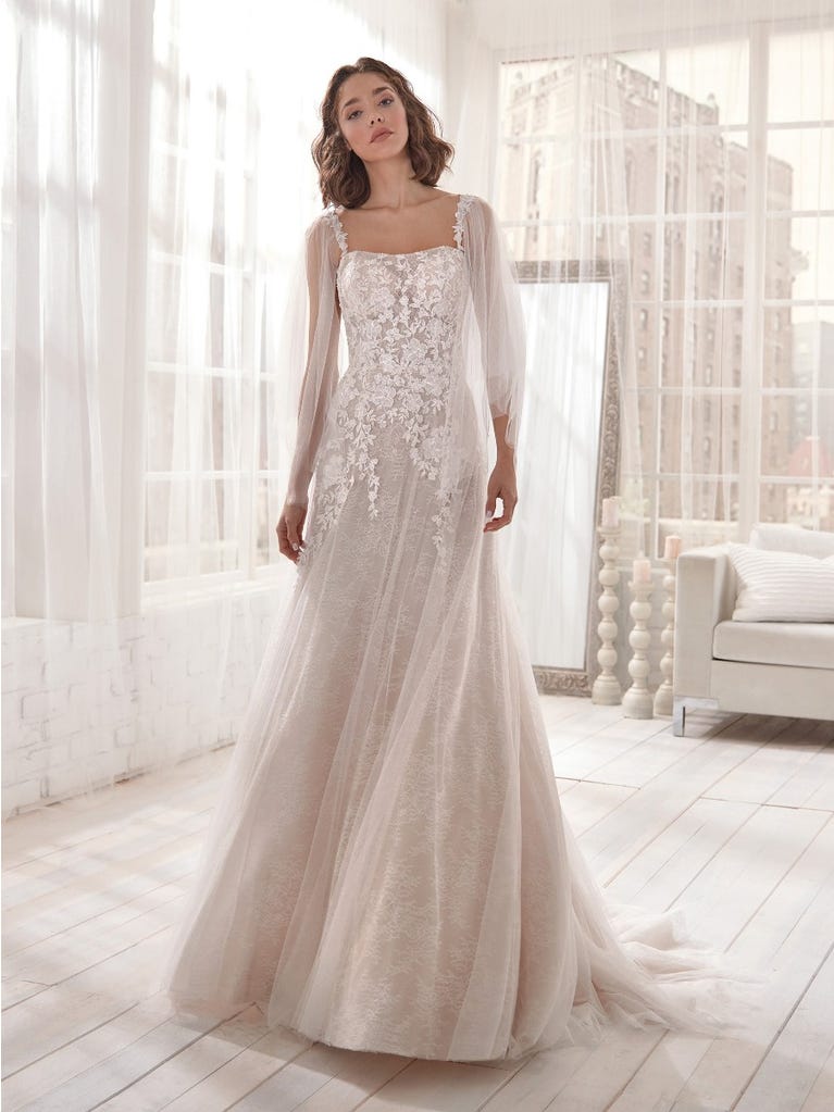 Romantic mermaid wedding dress of light pink Chantilly lace with plunging V-neck that continues on the sleeves. The keyhole opening in back and the tulle overskirt add romanticism to this dreamy dress.