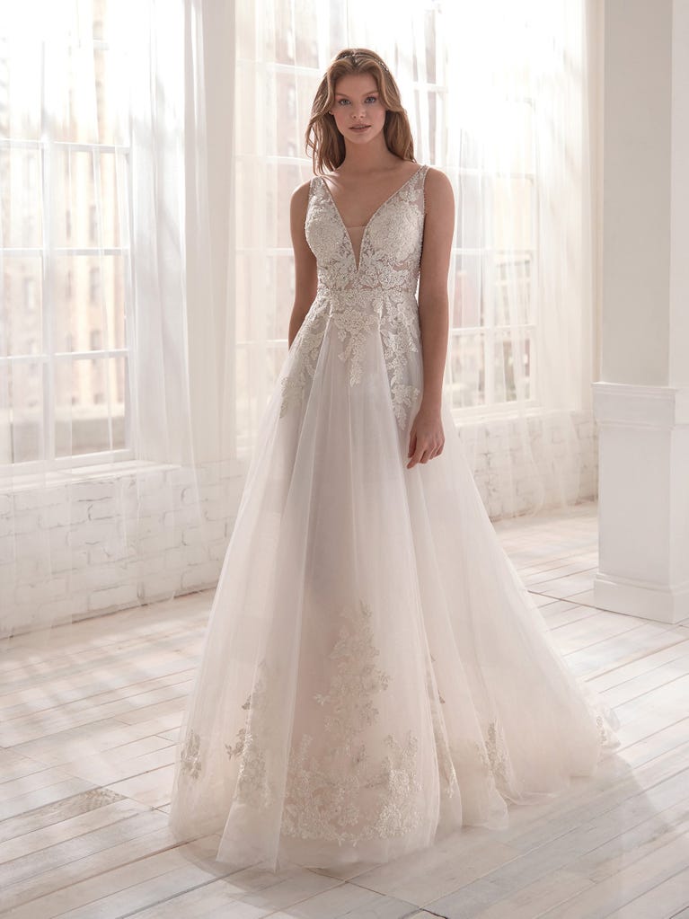 Romantic mermaid wedding dress of light pink Chantilly lace with plunging V-neck that continues on the sleeves. The keyhole opening in back and the tulle overskirt add romanticism to this dreamy dress.