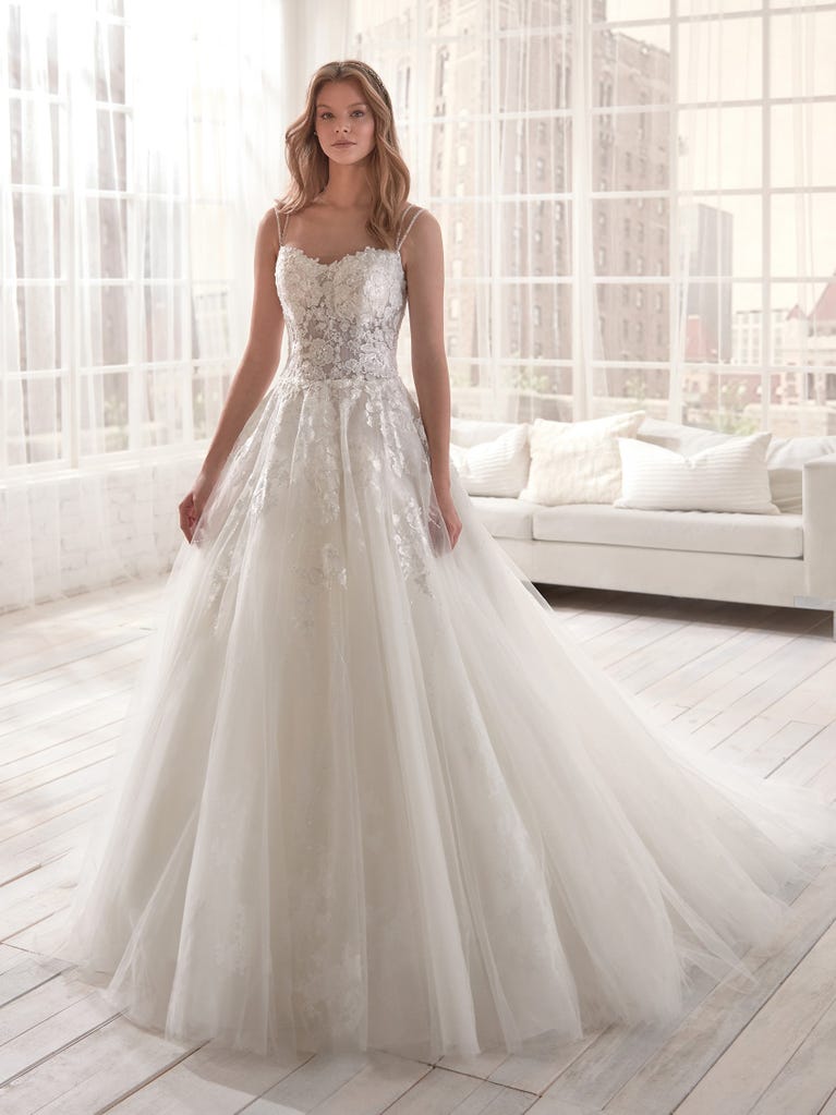 Romantic mermaid wedding dress of light pink Chantilly lace with plunging V-neck that continues on the sleeves. The keyhole opening in back and the tulle overskirt add romanticism to this dreamy dress.
