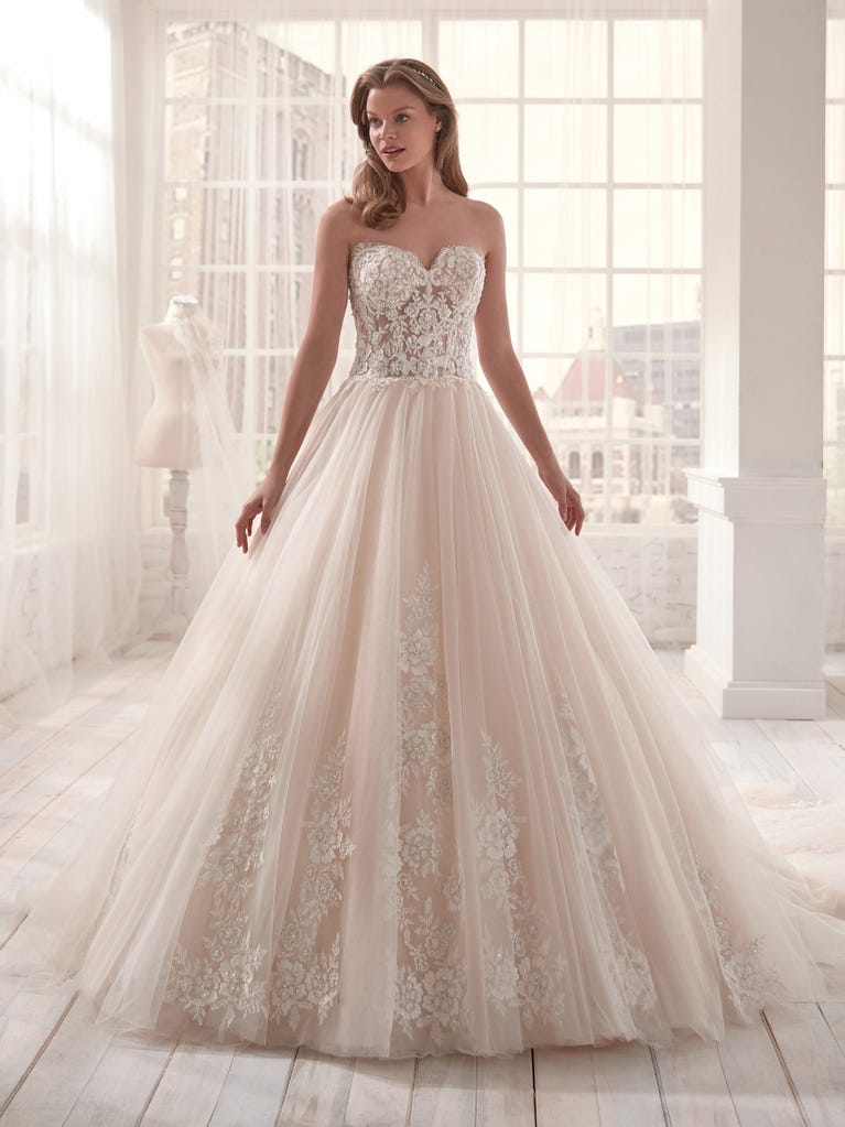 Romantic mermaid wedding dress of light pink Chantilly lace with plunging V-neck that continues on the sleeves. The keyhole opening in back and the tulle overskirt add romanticism to this dreamy dress.