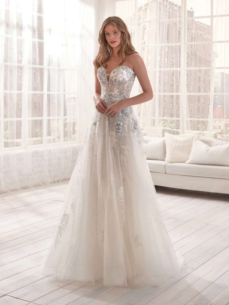 Romantic mermaid wedding dress of light pink Chantilly lace with plunging V-neck that continues on the sleeves. The keyhole opening in back and the tulle overskirt add romanticism to this dreamy dress.