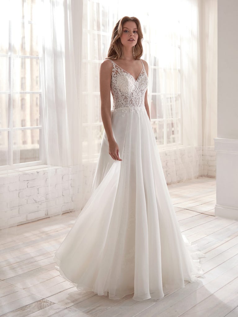 Romantic mermaid wedding dress of light pink Chantilly lace with plunging V-neck that continues on the sleeves. The keyhole opening in back and the tulle overskirt add romanticism to this dreamy dress.