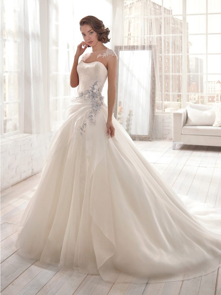 Romantic mermaid wedding dress of light pink Chantilly lace with plunging V-neck that continues on the sleeves. The keyhole opening in back and the tulle overskirt add romanticism to this dreamy dress.