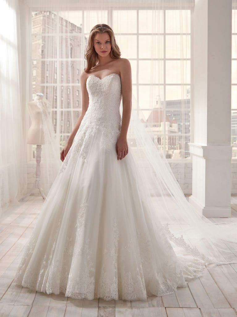 Romantic mermaid wedding dress of light pink Chantilly lace with plunging V-neck that continues on the sleeves. The keyhole opening in back and the tulle overskirt add romanticism to this dreamy dress.