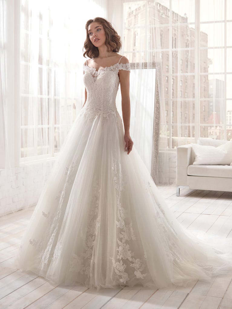 Romantic mermaid wedding dress of light pink Chantilly lace with plunging V-neck that continues on the sleeves. The keyhole opening in back and the tulle overskirt add romanticism to this dreamy dress.