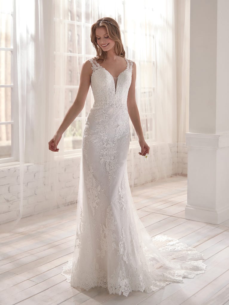Romantic mermaid wedding dress of light pink Chantilly lace with plunging V-neck that continues on the sleeves. The keyhole opening in back and the tulle overskirt add romanticism to this dreamy dress.