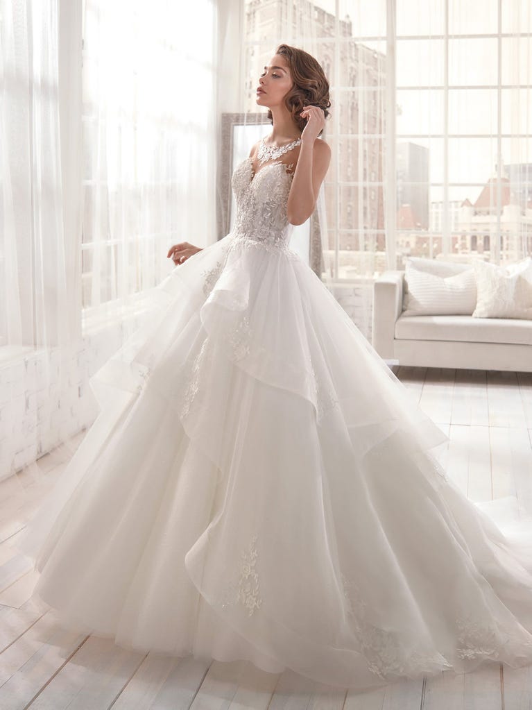 Romantic mermaid wedding dress of light pink Chantilly lace with plunging V-neck that continues on the sleeves. The keyhole opening in back and the tulle overskirt add romanticism to this dreamy dress.