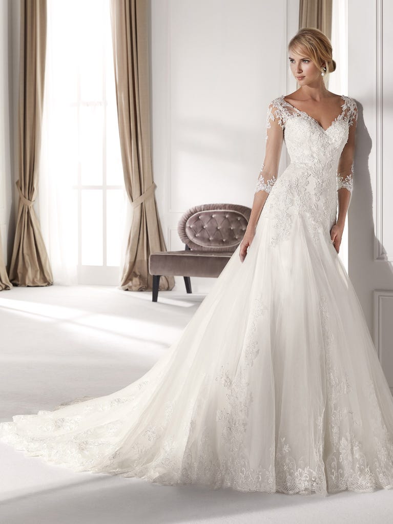 Fit & flare champagne tulle wedding dress with off-white guipure lace floral designs. The rounded neckline with tattoo-effect lace is highlighted with a refined, romantic 3D flower on the shoulder.