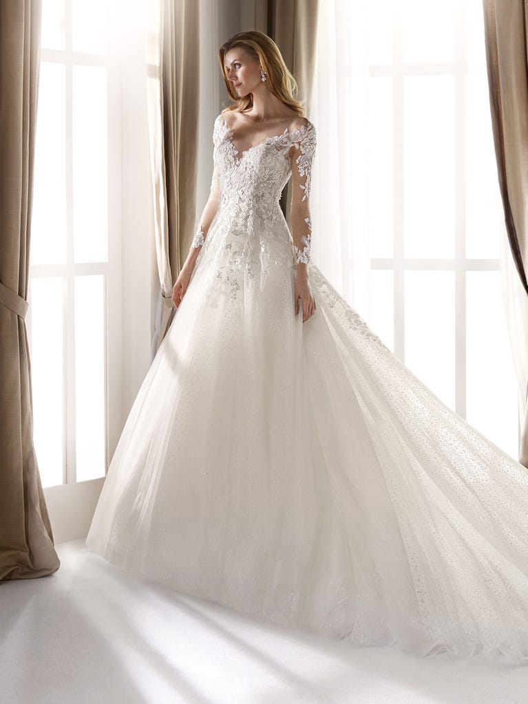 Fit & flare champagne tulle wedding dress with off-white guipure lace floral designs. The rounded neckline with tattoo-effect lace is highlighted with a refined, romantic 3D flower on the shoulder.
