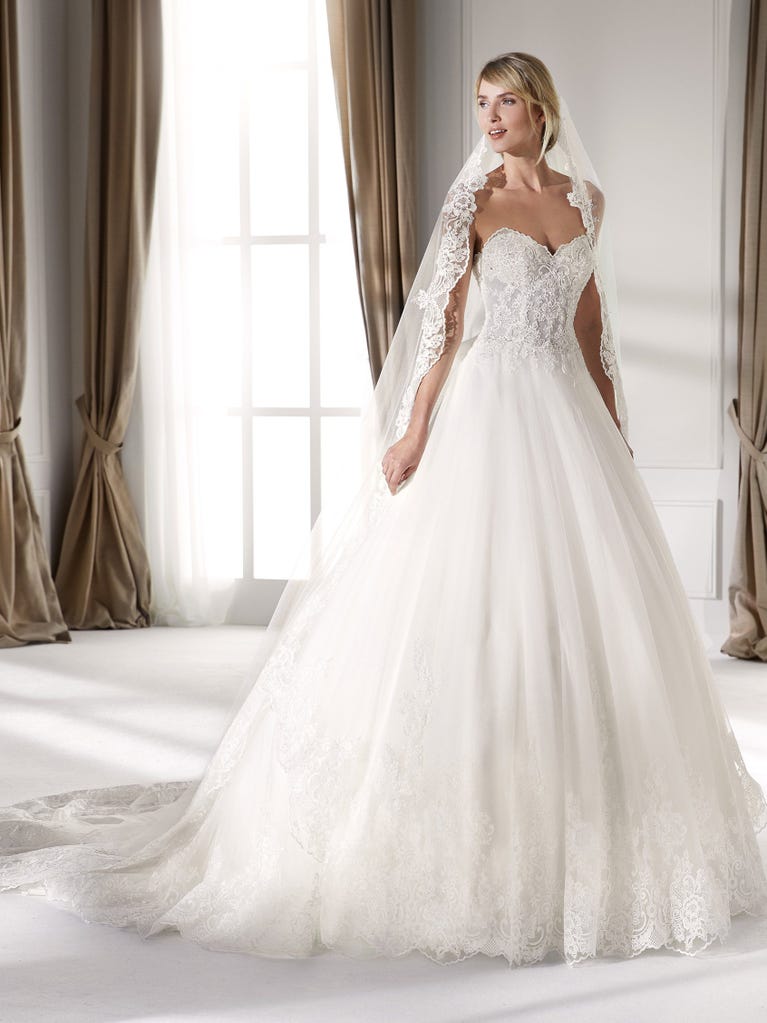 Fit & flare champagne tulle wedding dress with off-white guipure lace floral designs. The rounded neckline with tattoo-effect lace is highlighted with a refined, romantic 3D flower on the shoulder.