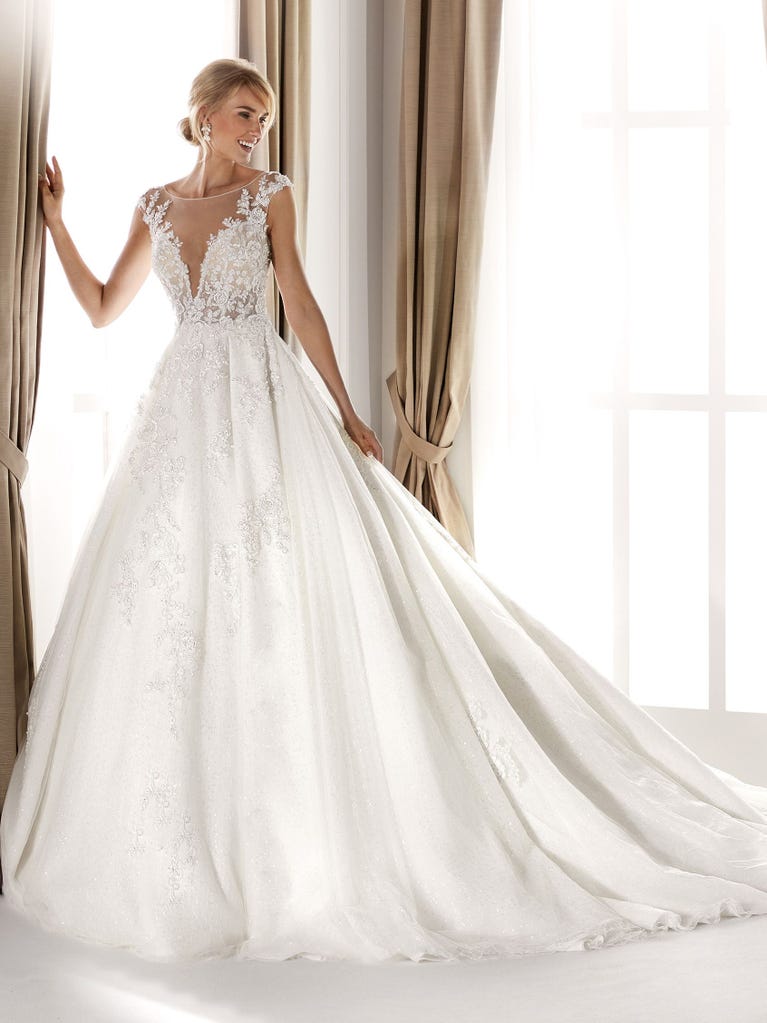 Fit & flare champagne tulle wedding dress with off-white guipure lace floral designs. The rounded neckline with tattoo-effect lace is highlighted with a refined, romantic 3D flower on the shoulder.