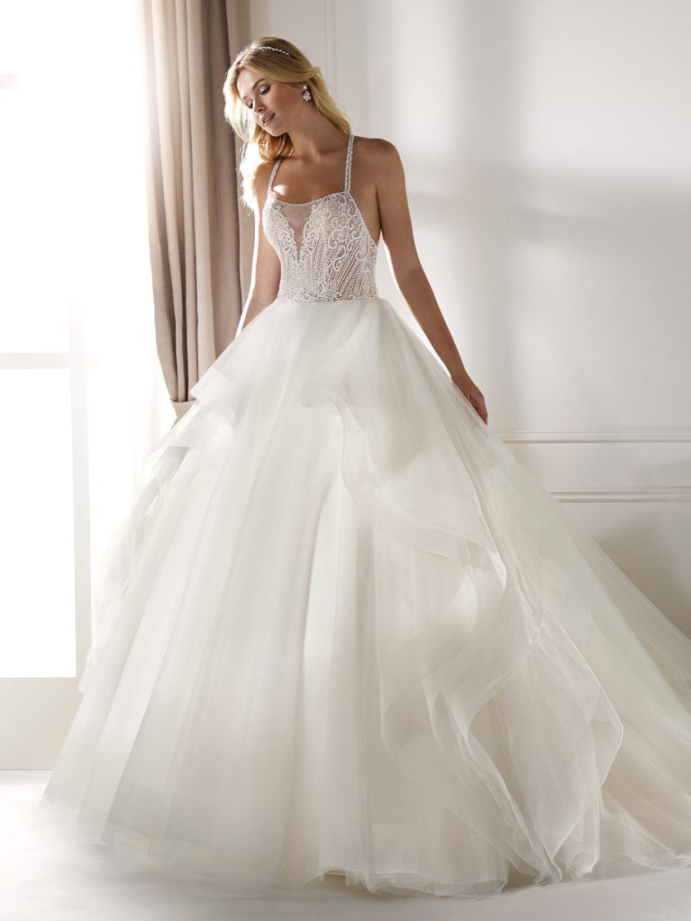 Romantic mermaid wedding dress of light pink Chantilly lace with plunging V-neck that continues on the sleeves. The keyhole opening in back and the tulle overskirt add romanticism to this dreamy dress.