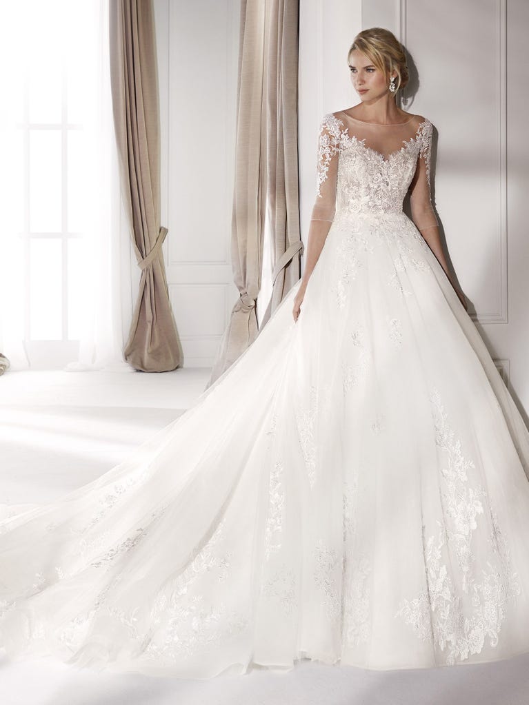 Fit & flare champagne tulle wedding dress with off-white guipure lace floral designs. The rounded neckline with tattoo-effect lace is highlighted with a refined, romantic 3D flower on the shoulder.