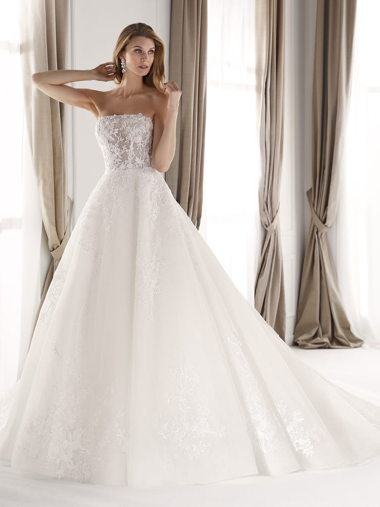 Fit & flare champagne tulle wedding dress with off-white guipure lace floral designs. The rounded neckline with tattoo-effect lace is highlighted with a refined, romantic 3D flower on the shoulder.