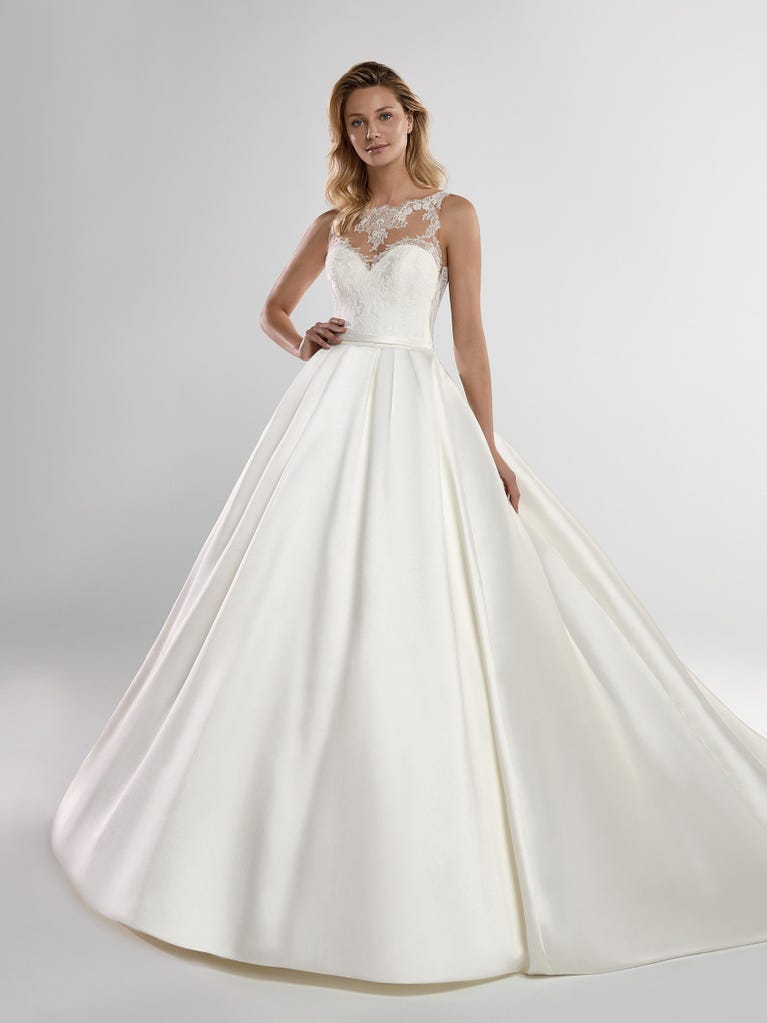 Fit & flare champagne tulle wedding dress with off-white guipure lace floral designs. The rounded neckline with tattoo-effect lace is highlighted with a refined, romantic 3D flower on the shoulder.