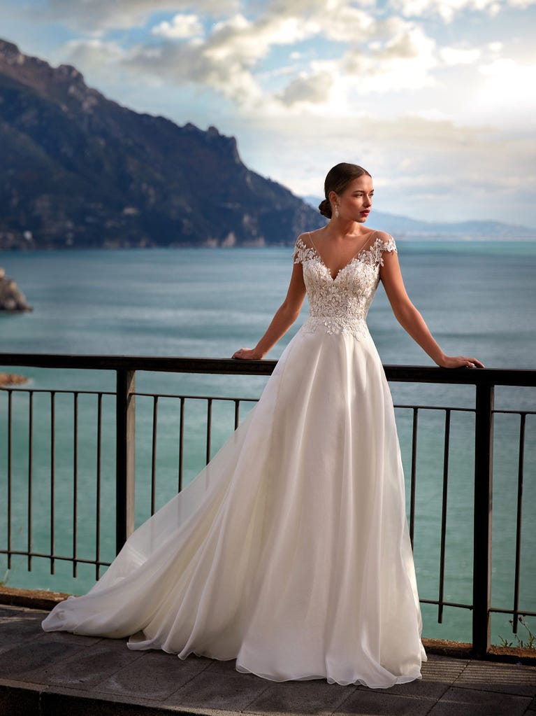 Flared wedding dress with voluminous yet lightweight tulle skirt with lace embroidered with floral motifs. For brides who dream of a romantic, feminine dress to say “I do.”