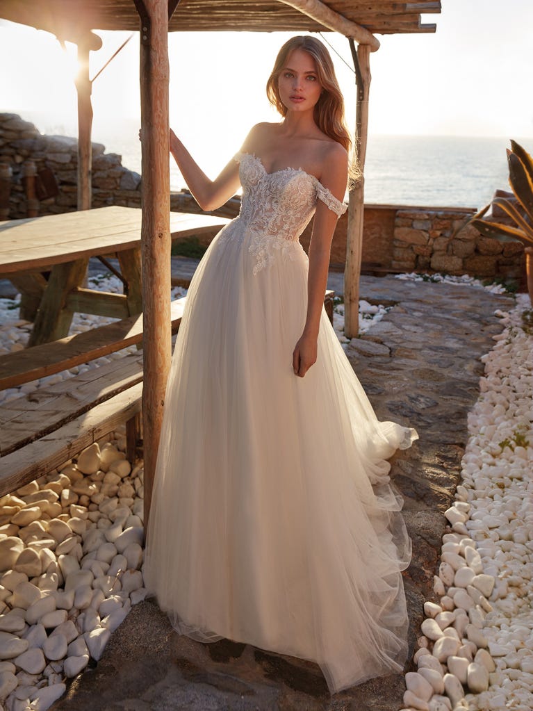 Mermaid dress of embroidered champagne tulle with plunging V-neck in front and back and short sleeves. The tulle overskirt adds volume and romanticism.
