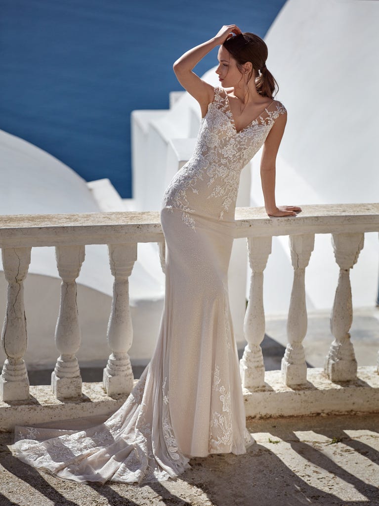 Flared wedding dress with crepe skirt and a tulle cape embroidered with silver beads. The three-dimensional flowers and minimalist, geometric superimpositions of fabrics create a contemporary, unique look for brides who want to surprise.