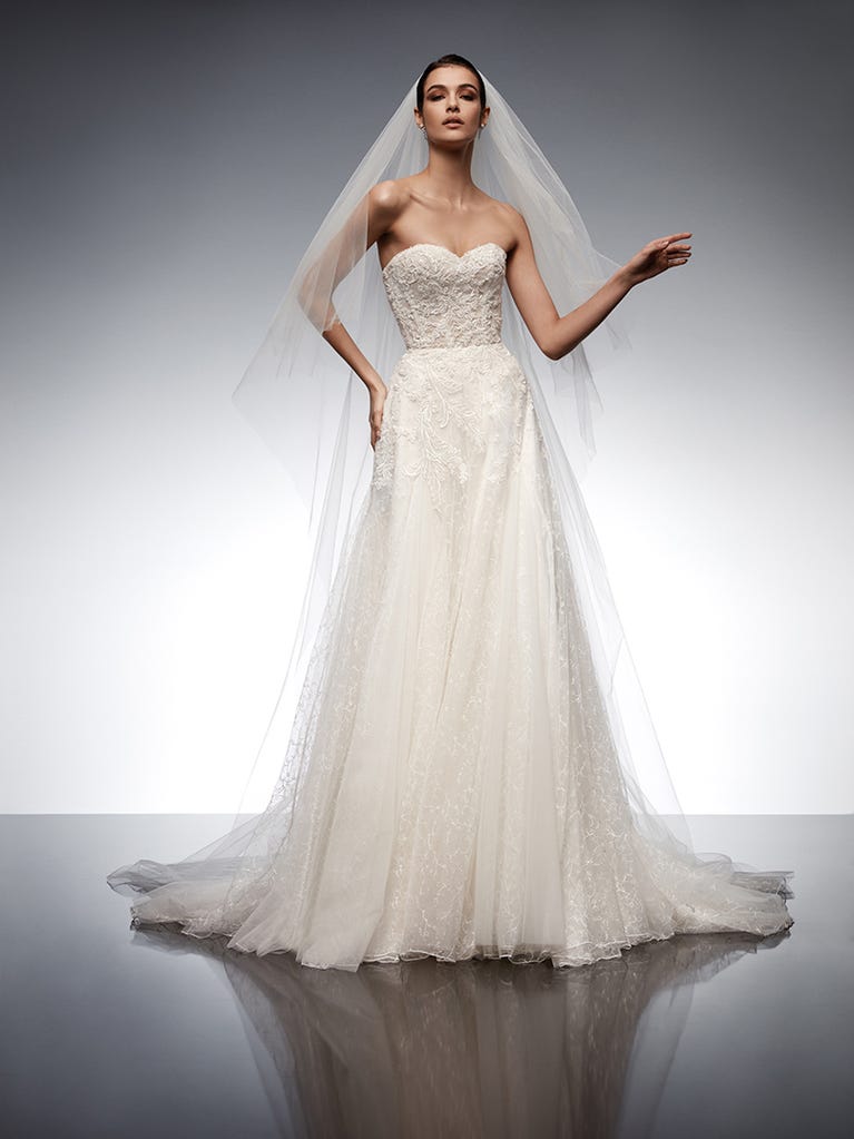Beautiful A-line wedding dress in champagne tulle with embroidered beading and elegant 3D flowers. The straps expose the back with an elegant neckline.