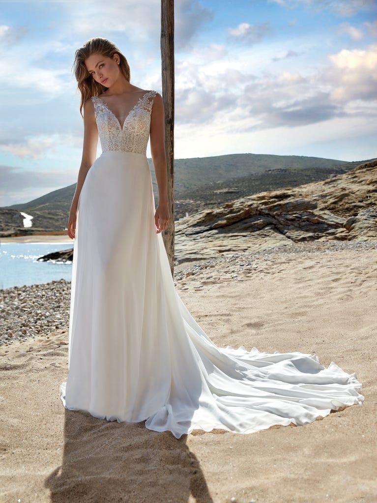 Mermaid dress of embroidered champagne tulle with plunging V-neck in front and back and short sleeves. The tulle overskirt adds volume and romanticism.
