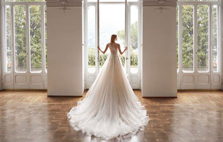 Modella di spalle che indossa un lungo abito da sposa a principessa con strascico in tulle.