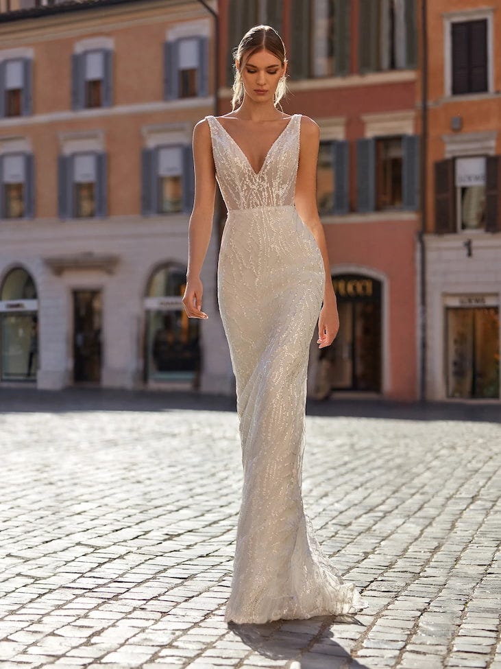 Donna che si trova in strada con un vestito da sposa con scollo a V e capelli raccolti con ciuffi che scenono ai lati